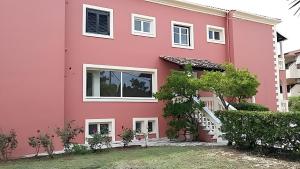 a pink house with white windows at 2BR Apt Kitchenette Pool 6 in Gouvia