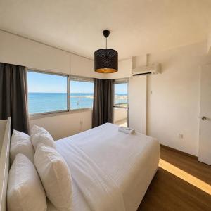 a bedroom with a bed with a view of the ocean at 2BR Seafront Apt in center with community pool in Larnaca +10 photos