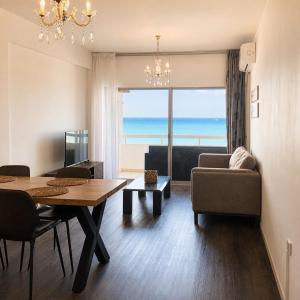 a living room with a table and a view of the ocean at 2BR Seafront Apt in center with community pool in Larnaca