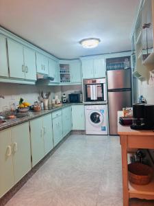 a kitchen with blue cabinets and a washer and dryer at O lar da praia in Corcubión