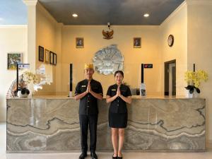 two people are standing in front of a counter at Mahkota Hotel in Genteng-kulon