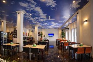 a restaurant with tables and chairs and a ceiling with clouds at Mahkota Hotel in Genteng-kulon