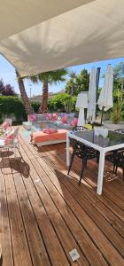 a wooden deck with a table and chairs and umbrellas at Chambre Gaëlle et Brian in Cardet