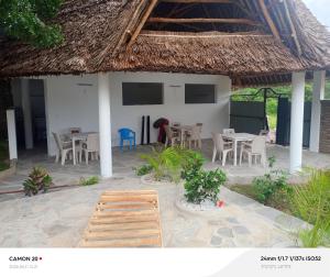 a house with tables and chairs and a thatched roof at Tranquil villa in Watamu