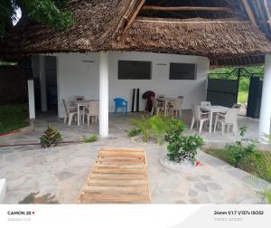 a house with chairs and tables and a thatched roof at Tranquil villa in Watamu +7 photos