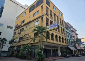 a yellow building with a palm tree in front of it at The Royal Pattaya Cantina Near Walking Steer in Pattaya South