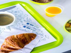 a tray with a piece of bread and a cup of coffee at Ibis Budget Fréjus St Raphaël centre plages gare TGV in Fréjus