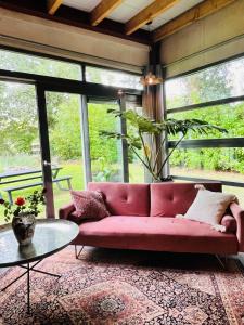 a pink couch in a room with windows at Stijlvol Atelier in het groen in Liempde