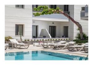a pool with lounge chairs and a palm tree next to a building at Summer Dream in Rethymno