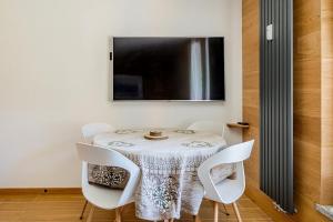 a dining room table with white chairs and a television at Chalet Campiglio Mountain View - Guardabassi Collection in Madonna di Campiglio
