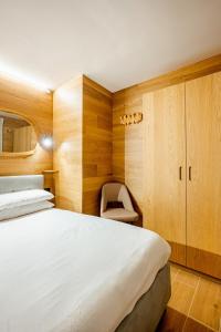 a bedroom with a large bed and a chair at Chalet Campiglio Mountain View - Guardabassi Collection in Madonna di Campiglio