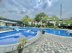 a large swimming pool with blue water at Mahkota Hotel in Genteng-kulon