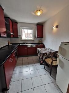 a small kitchen with red cabinets and a table at Ferienwohnung Münsingen zentrum in Münsingen +2 photos