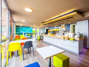 a fast food restaurant with tables and yellow chairs at ibis budget Rennes Chantepie - Hôtel rénové in Chantepie