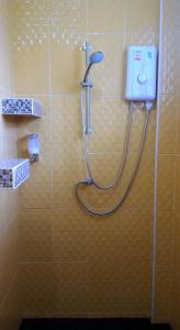 a shower in a bathroom with a hose on a wall at Baan Benjathip in Amphawa