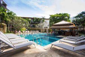 einen Pool mit Liegestühlen und ein Hotel in der Unterkunft Baan Karon Resort in Karon Beach