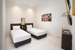 a room with two beds and a television in it at Mahkota Hotel in Genteng-kulon +13 photos