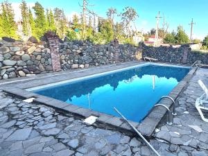 a swimming pool with a stone wall and blue water at Old House Ureki in Ureki