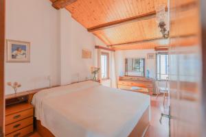 a bedroom with a white bed and a wooden ceiling at Domina House by ElbaSummer in Marciana