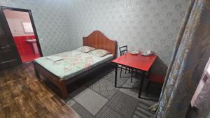 a small bedroom with a bed and a red table at Гостиница Саян in Shymkent