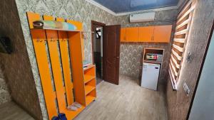 a small kitchen with orange cabinets and a refrigerator at Гостиница Саян in Shymkent