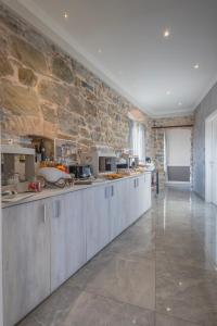 a kitchen with gray cabinets and a stone wall at PRIMA FILA Premium Guest House in Sanremo