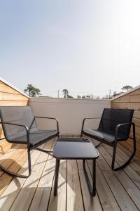 three chairs and a coffee table on a balcony at Hôtel La Chaumière-Les Pastourelles in Capbreton