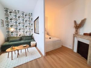 a living room with a green couch and a fireplace at Le Tinqueux Chic-Studio rénové proche centre reims in Reims