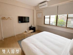 a bedroom with a white bed and a tv at Littlesay in Tainan