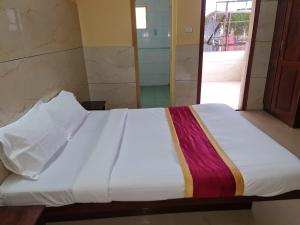 a bed in a room with a white sheets and a window at Hotel Royal Park in Mangalore