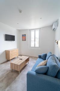 a living room with a blue couch and a coffee table at Hôtel La Chaumière-Les Pastourelles in Capbreton