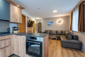 a kitchen and a living room with a couch at Maiskogelblick Apartments by we rent in Piesendorf