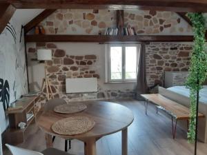 a living room with a table and a stone wall at Gîte de l'Ancienne Forge in Epfig