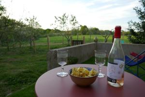 a bottle of wine and a bowl of food on a table at Ondas Eco-Gîtes in Arsagne