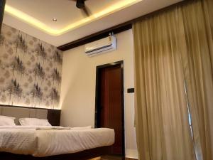 a hotel room with two beds and a window at Hotel J VIN PALACE in Mysore +2 photos