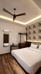 a bedroom with a white bed and a ceiling fan at Hotel J VIN PALACE in Mysore