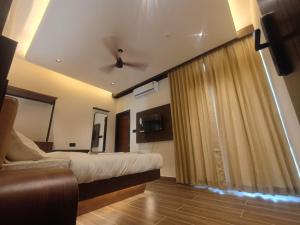 a bedroom with a bed and a couch in a room at Hotel J VIN PALACE in Mysore