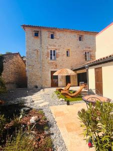 an outdoor patio with two chairs and an umbrella at Maison Laroque & Spa in Bellefont-La Rauze