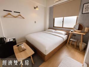 a small bedroom with a bed and a table at Littlesay in Tainan