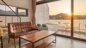 a living room with a leather couch and a balcony at Yeosu Bokja Spa Pension in Yeosu