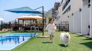 a girl walking a white dog by a pool at Yeosu Bokja Spa Pension in Yeosu