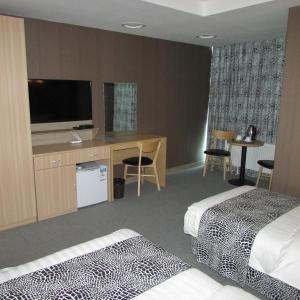 a hotel room with two beds and a desk with a television at J Hotel in Ulaanbaatar