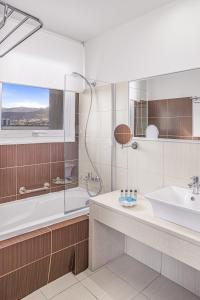 ein Badezimmer mit Badewanne, Waschbecken und Dusche in der Unterkunft Glaros Beach Hotel in Hersonissos