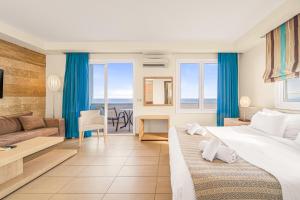 ein Hotelzimmer mit einem großen Bett und einer Couch in der Unterkunft Glaros Beach Hotel in Hersonissos