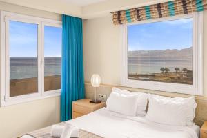 ein Schlafzimmer mit einem Bett und zwei großen Fenstern in der Unterkunft Glaros Beach Hotel in Hersonissos
