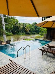 a large swimming pool with a bench and a table at Yala River Face Inn in Tissamaharama