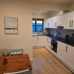 a kitchen with white cabinets and a wooden table at 18 Clifden Court in Clifden
