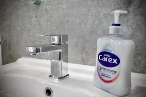 a bottle of soap sitting on top of a bathroom sink at Spacious 2 Bed Flat - 5 mins to St Helens Centre - Free Parking in Saint Helens