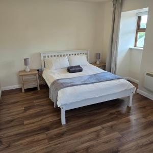 a bedroom with a white bed and wooden floors at 18 Clifden Court in Clifden