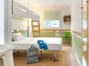 a small room with a bed and a backpack at ibis budget Compiègne Noyon in Noyon